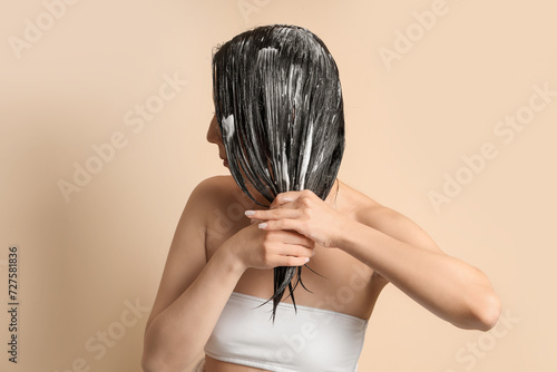 Konstfotografi Young woman applying hair mask on beige background, closeup