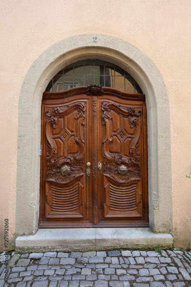Two sturdy, weathered wooden doors reside atop a lofty building, standing as a gateway to unknown possibilities.
