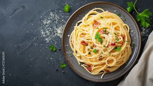 Delicious spaghetti carbonara served on a dark plate, garnished with parsley