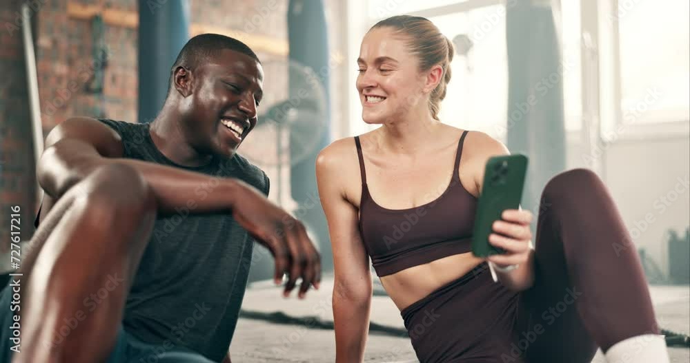 Happy people, fitness and phone on break at gym for social media, communication or networking. Interracial man and woman with smile on mobile smartphone in relax after workout, exercise or training Happy people, fitness and phone on break at gym for social media, communication or networking. Interracial man and woman with smile on mobile smartphone in relax after workout, exercise or training