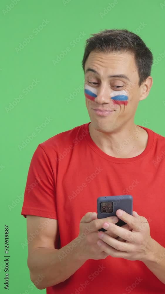 Russian supporter looking at his mobile smiling and showing it. Russian supporter looking at his mobile smiling and showing it.