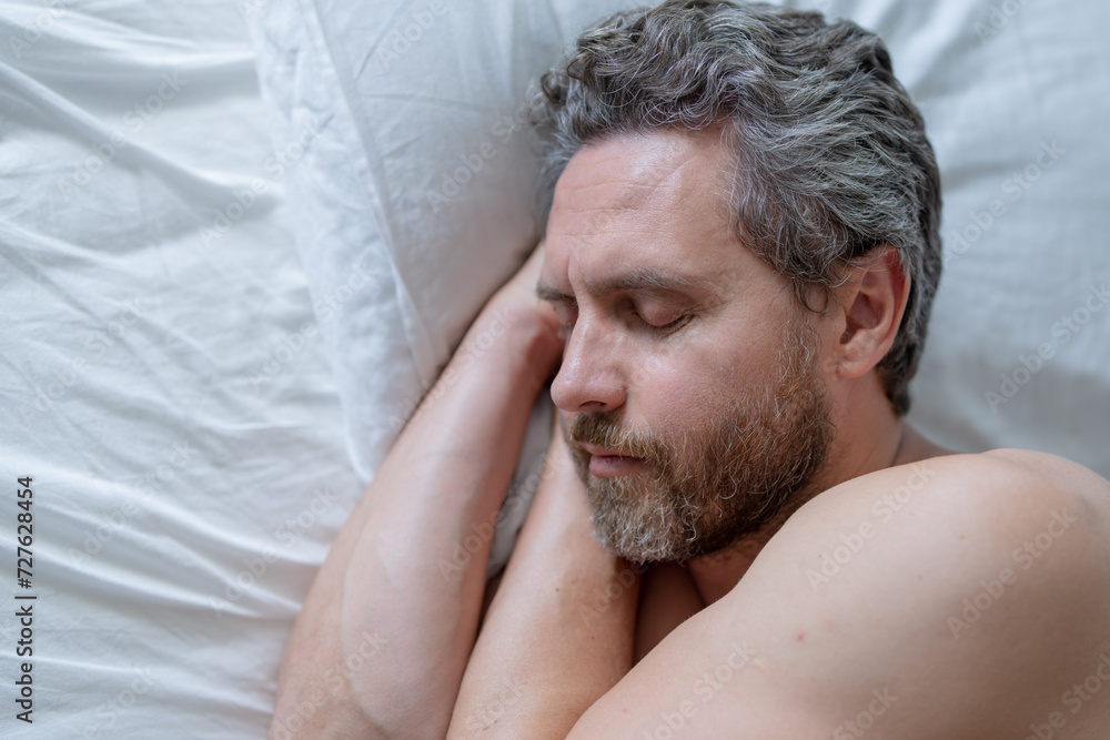 Fototapeta premium Man sleeping in white bed. Sexy shirtless man sleeping in bed at bedroom. Hispanic mature man sleeping at home at morning. Good sleep. Man sleeping in bed. People bedtime, rest sleep.
