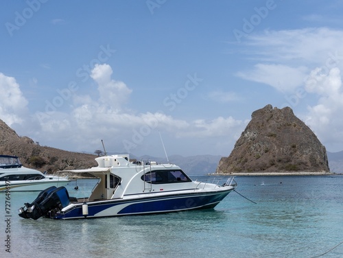 A regular sized white and blue speedboat is anchored at the beach and ready to go across the ocean. © DS Showcase