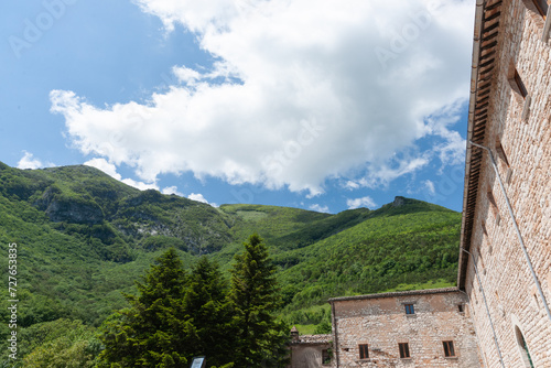 Typical stone and brick building wall under lush green mountain