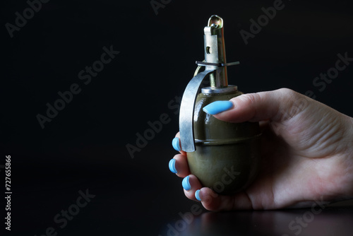 A woman's hand with a blue manicure holds a hand grenade. Concept of women's service in the Israeli army. Black background. Israel Defense Forces. Photo photo