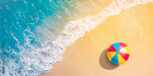 Soft ocean wave on the sandy beach, background? Colorful beach ball on yellow sand and turquoise blue ocean waves. Aerial view with copy space for text by Vita  photo