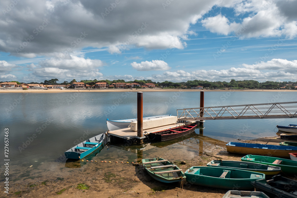 Paisagem envolvente: Cais fluvial com alguns pequenos barcos nas margens da água em Vieux Boucau les Bains, emoldurado por algumas nuvens num Dia sereno no País Basco francês