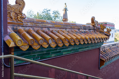 Ornate Chinese roof tiles of an old palace complex with elegant and intricate carvings, a color combination of golden shiny yellow and jade green. photo