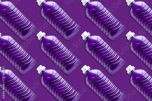 Lots of purple plastic bottles for washing gel, liquid detergent, bleach, and fabric softener, on a purple background.
