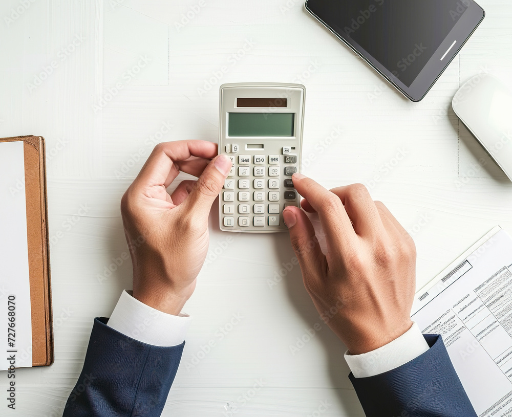 Accountant or businessman using calculator on white office desk to count income and outcome, top view Accountant or businessman using calculator on white office desk to count income and outcome, top view