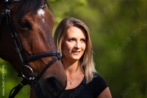 Young brunette woman in head portrait next to her horse. Sharp main subject.