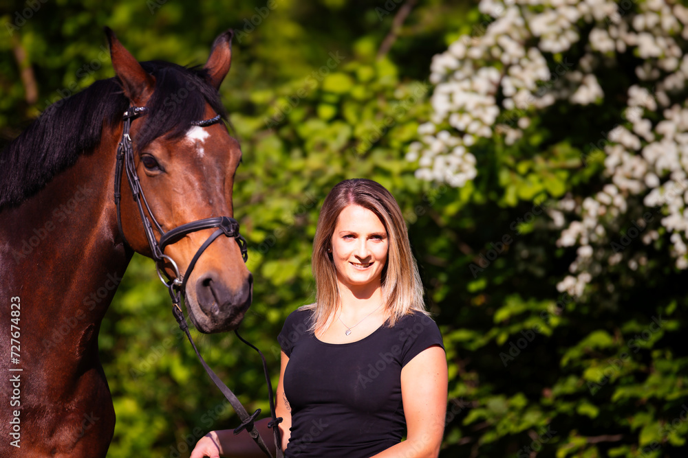 Fototapeta premium Young brunette woman in head portrait next to her horse. Sharp main subject.