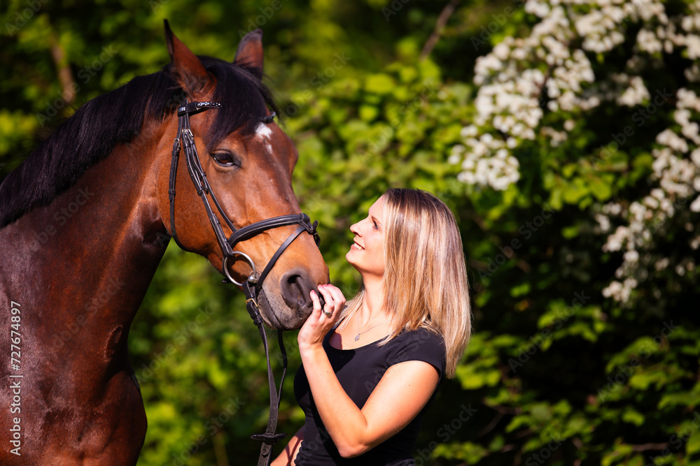 Obraz premium Young brunette woman in head portrait next to her horse. Sharp main subject.