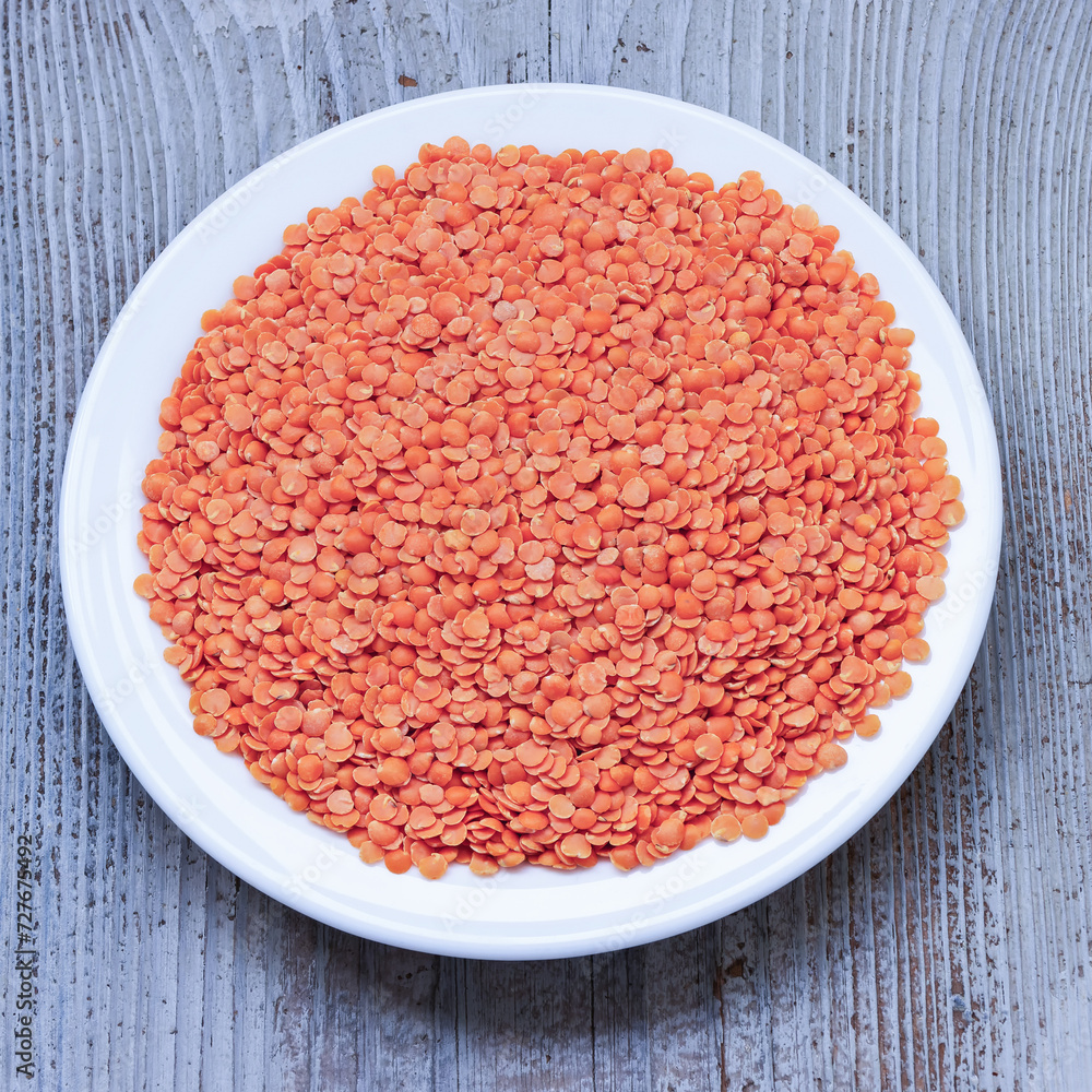 Top view of a pile of split red lentils on a white plate Top view of a pile of split red lentils on a white plate