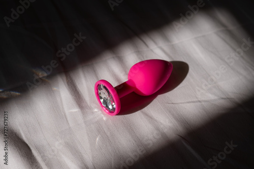 Pink silicone anal plug on a white sheet. 