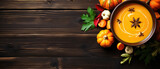 Pumpkin soup with pumpkin and autumn leaves on a wooden table, top view. Horizontal banner