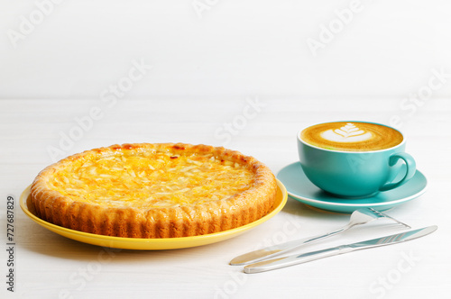 Homemade orange and apple pie and cup of coffee cappuccino on white wooden table. Copyspace.