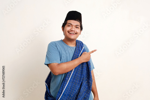 Asian muslim boy pointing sideways with happy face expression photo