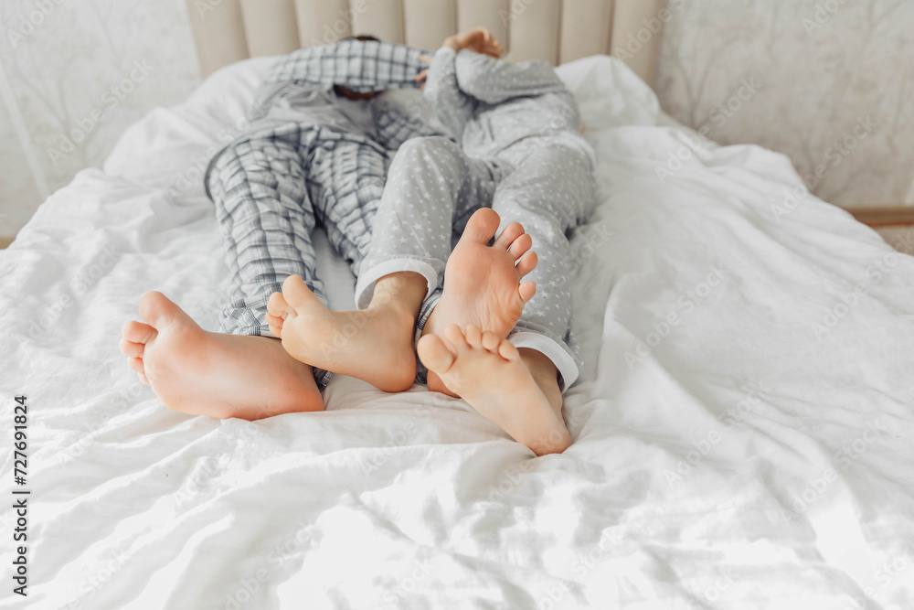 the bare, clean feet of two children, offspring, lying side by side under the same blanket on the bed. morning relaxation, cozy rest. cute pictures of baby feet the bare, clean feet of two children, offspring, lying side by side under the same blanket on the bed. morning relaxation, cozy rest. cute pictures of baby feet