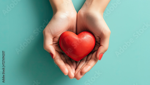 Hands clasping a red heart against a backdrop of blue