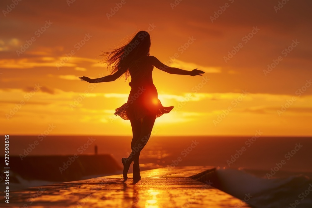 Silhouette of a woman dancing at sunset, epitomizing freedom against a golden seascape.

