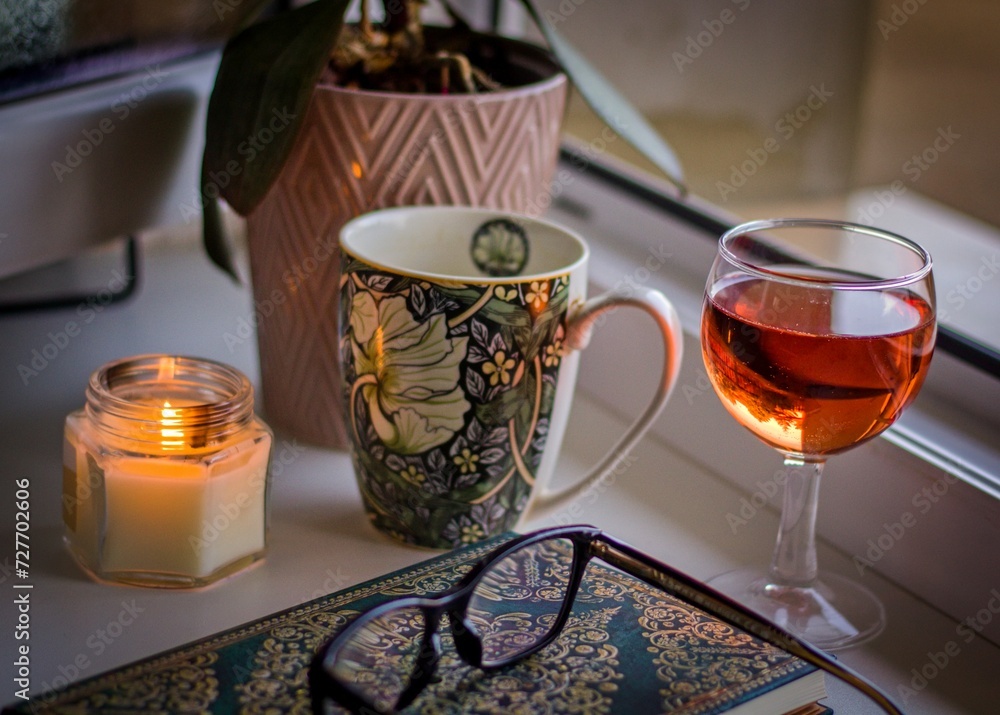 Still life with a candle, a mug and a glass of wine on a window sill Still life with a candle, a mug and a glass of wine on a window sill
