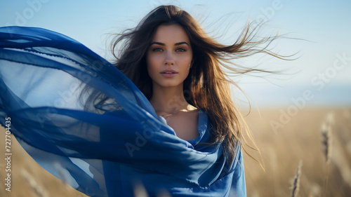 Beautiful young woman with blue scarf on the wind in the spring photo