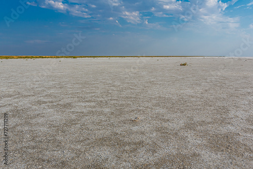 Bright sunny day on salt lake Boltul (Russia, Volrograd) with Cumulus, Cumulostratus clouds. Fluffy white clouds in the blue sky in summer. On the surface of the lake there is a white-brown salt marsh photo