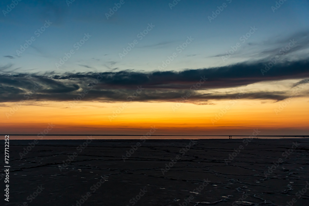 Sunset or sunrise on salt lake Elton (Russia) Tall altocumulus and cirrocumulus clouds against the background of salt marsh and a large amount of brine. Evening or morning. Sunset or sunrise on salt lake Elton (Russia) Tall altocumulus and cirrocumulus clouds against the background of salt marsh and a large amount of brine. Evening or morning.