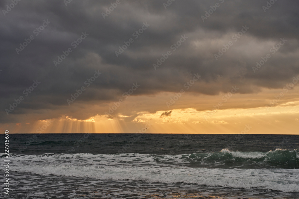 Obraz premium amanecer con nubes de tormenta en una playa turística del mediterráneo 