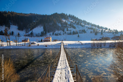 Landscape with a narrow bridge suspended over a river in a rural area in Romania © sebi_2569