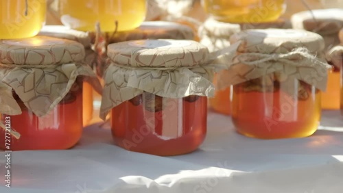 Rows of jars of bright yellow orange honey at the outdoor market