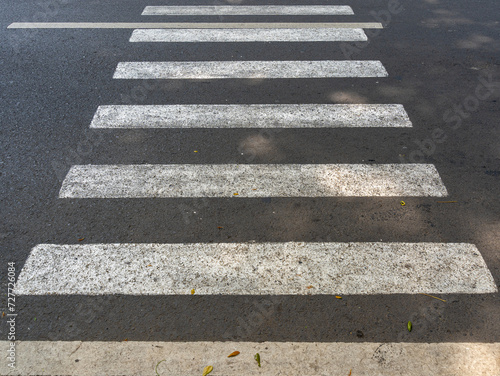 A zebra crosswalk on a grey asphalt road.