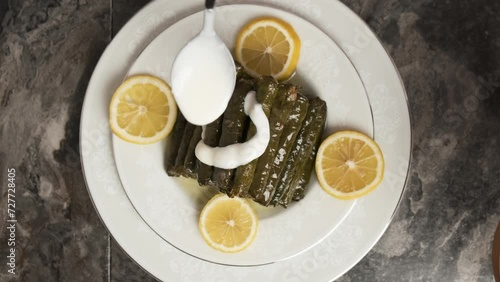 Adding Yoghurt Sauce on Turkish Traditional Food Yaprak Sarma. It Means Stuffed Grape Leaves. Also Known as Dolma. Ready to Eat. The Meal Filled with Rice and Mince. Slow Motion Close Up Shot.