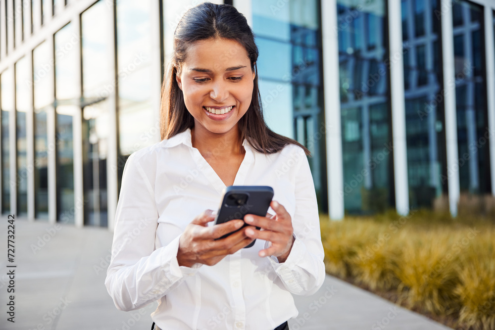 Smiling business woman using phone outside modern office Smiling business woman using phone outside modern office
