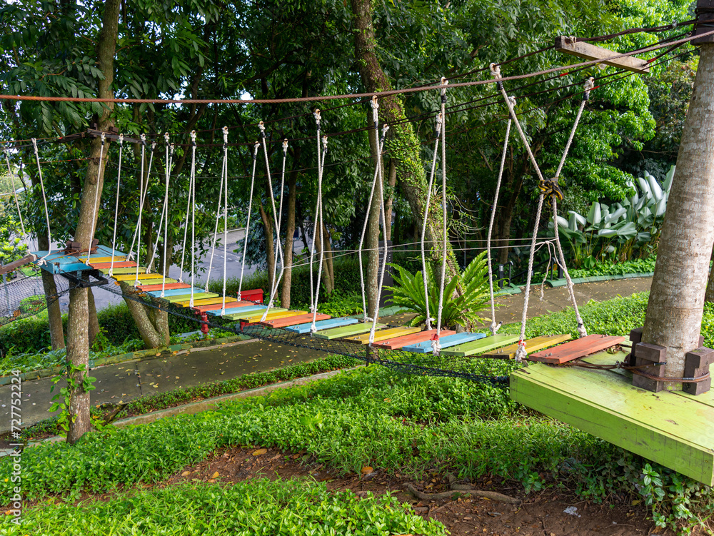 A hanging bridge consisting of colorful wood planks and rope arrangement. A hanging bridge consisting of colorful wood planks and rope arrangement.