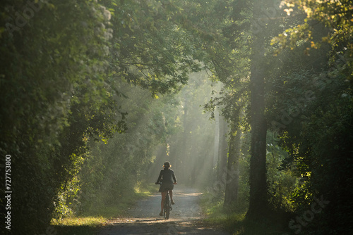 Femme cycliste de dos, sur un chemin en foret, cyclotourisme nature