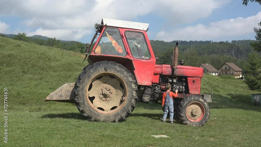 Little boy trying to repair tractor at the farm Little boy trying to repair tractor at the farm
