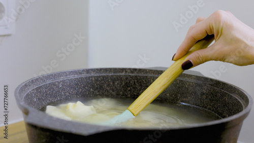 A young woman cooks dumplings, ravioli in a saucepan