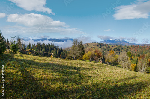 Late autumn mountain morning scene with snow covered tops in far and foggy clouds in valleys. Picturesque traveling, seasonal, nature and countryside beauty concept scene. Carpathians, Ukraine.