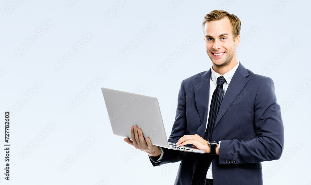 Happy smiling young business man wear black suit, necktie using laptop computer, isolated gray grey background, copy space area for ad text. Businessman holding notebook at studio concept image. Happy smiling young business man wear black suit, necktie using laptop computer, isolated gray grey background, copy space area for ad text. Businessman holding notebook at studio concept image.