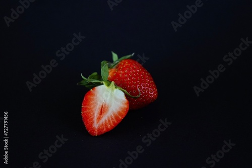 Red ripe strawberries lie on a black background