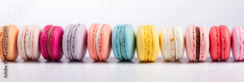 Vibrant, diverse macarons in a row on a reflective white surface. Ideal for bakery ads, dessert menus, or art projects. Plenty of copy space.