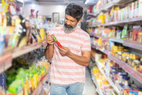 Happy indian man shopping for groceries at the supermarket.bearded Man checking product at grocery store.