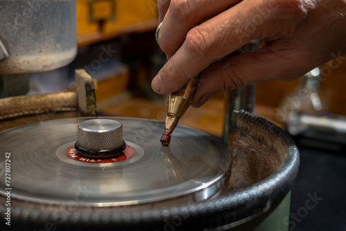 Stonecutter faceting red garnet stone on the metal dop stick into the round stone shape.