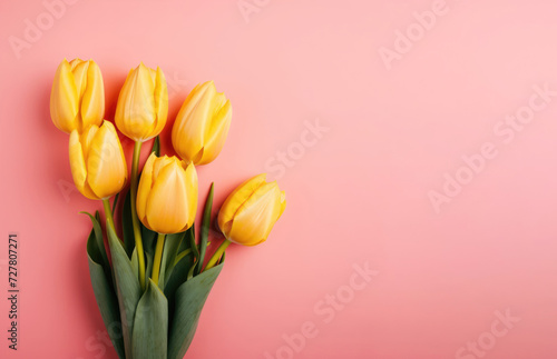 Bouquet of yellow tulips on a pink background, top view