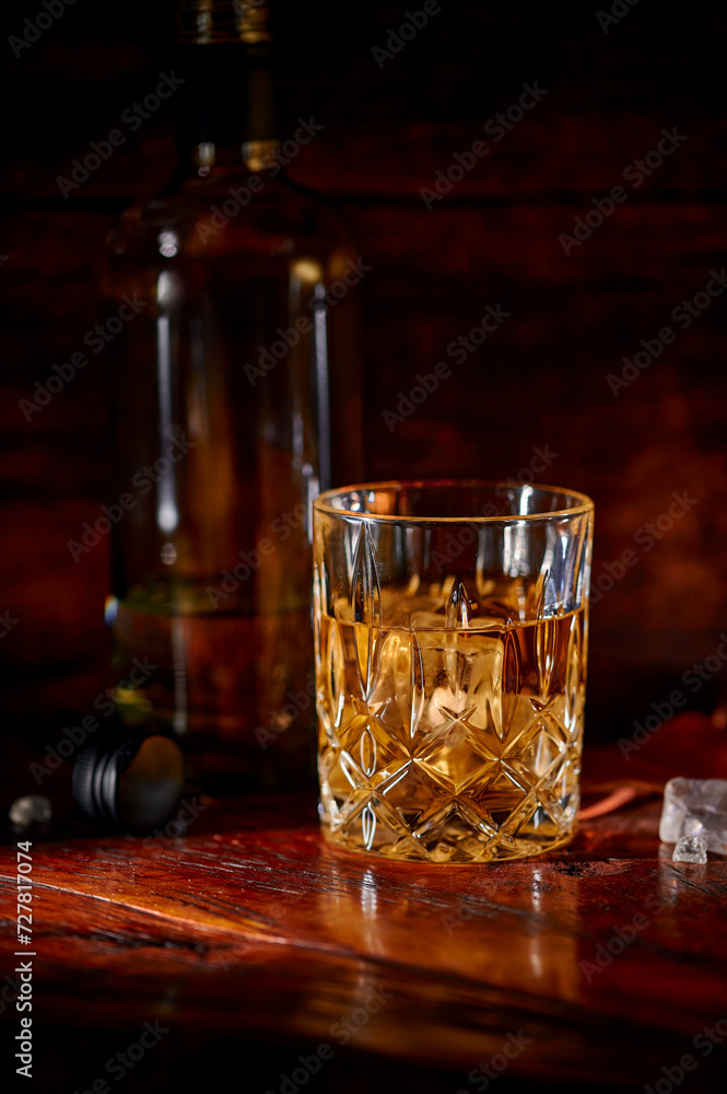 Whisky in a glass with ice on rustic wood Whisky in a glass with ice on rustic wood