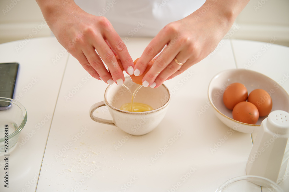 Close-up of female hands cracking egg into bowl on kitchen table. Process of cooking pecan pie in home kitchen for American Thanksgiving Day. Close-up of female hands cracking egg into bowl on kitchen table. Process of cooking pecan pie in home kitchen for American Thanksgiving Day.
