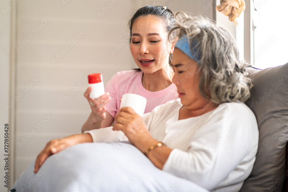 Portrait of love asian family senior mature mother and woman daughter care holding bottle tablet with pill and taking medicine with glass of water together.Healthcare senior people concept Portrait of love asian family senior mature mother and woman daughter care holding bottle tablet with pill and taking medicine with glass of water together.Healthcare senior people concept