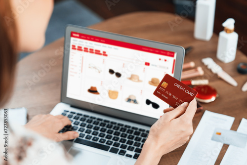 Woman shopping online on internet marketplace browsing for sale items for modern lifestyle and use credit card for online payment from wallet protected by utmost cyber security software